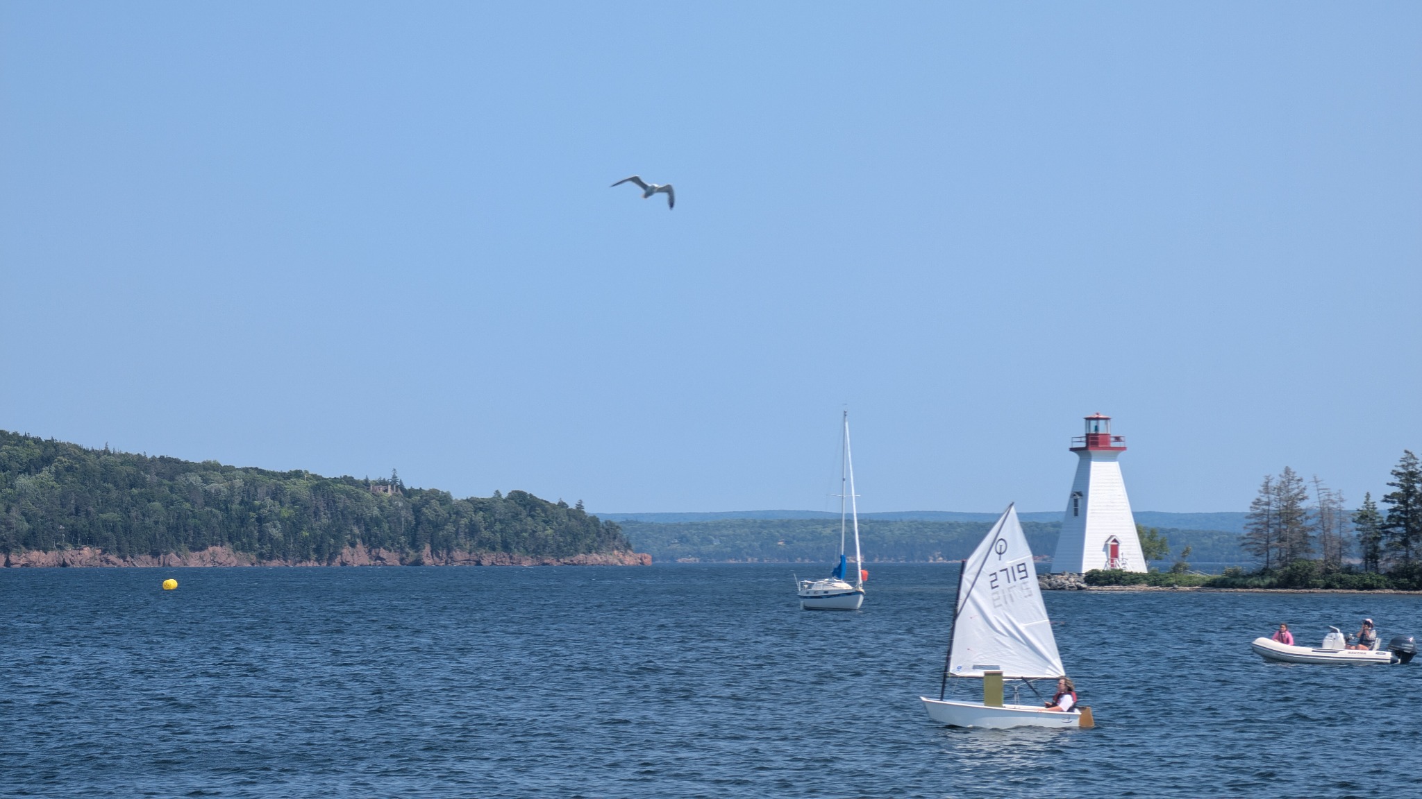 Sailboats and a lighthouse on the water in Cape Breton